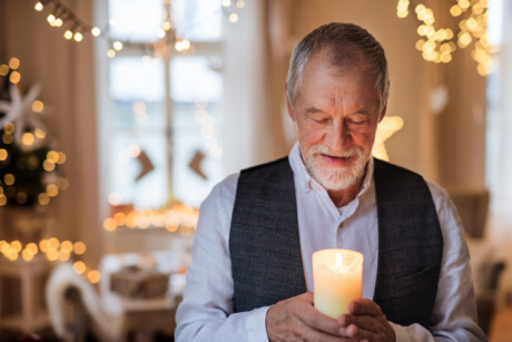 männlicher Senior blickt auf eine kerze männerdialoge dezember 2025